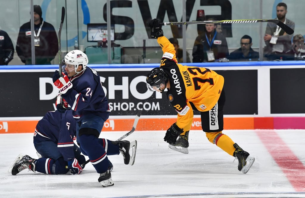 Matt Donovan (l-r), Andy Miele (M) (USA) und Dominik Kahun (r) (Deutschland) kämpfen um den Puck.