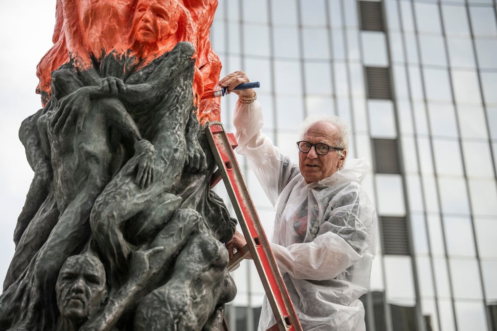 Der Künstler Jens Galschiot bemalt das Mahnmal „Säule der Schande“ oder englisch „Pillar of Shame“ mit roter Farbe.