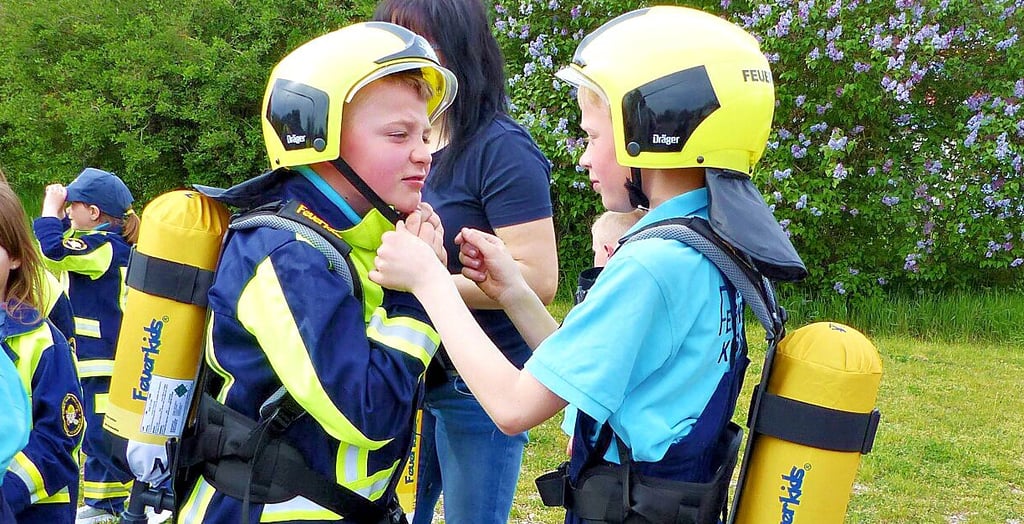 Matthes und Emil, Mitglieder der Karsdorfer Kinderfeuerwehr, helfen sich gegenseitig beim Anziehen der Ausrüstung.