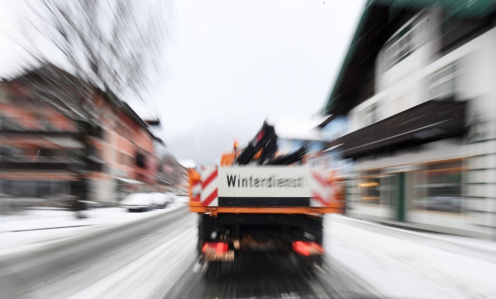 Ein Fahrzeug des Winterdienstes fährt über eine Straße.