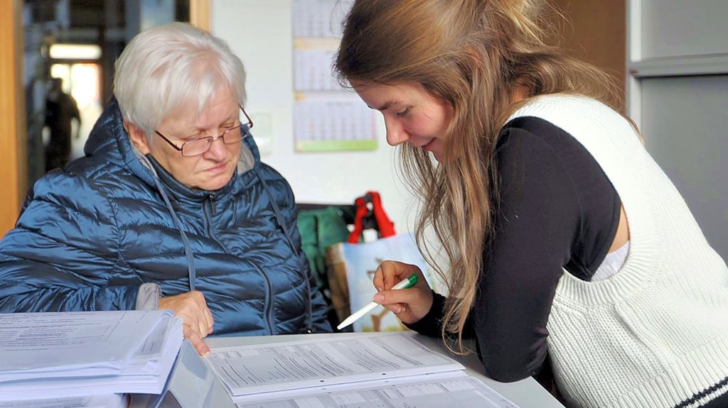 Eine Seniorin lässt sich beim Ausfüllen ihres Wohngeldantrages helfen.