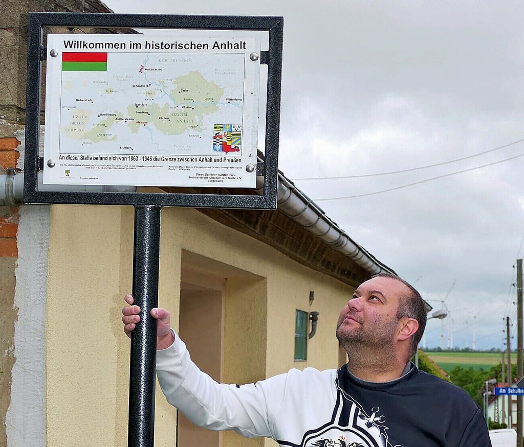 Mirco Breborowicz hält das neue Grenzschild an der Alslebener und Ascherslebener Grenze fest.
