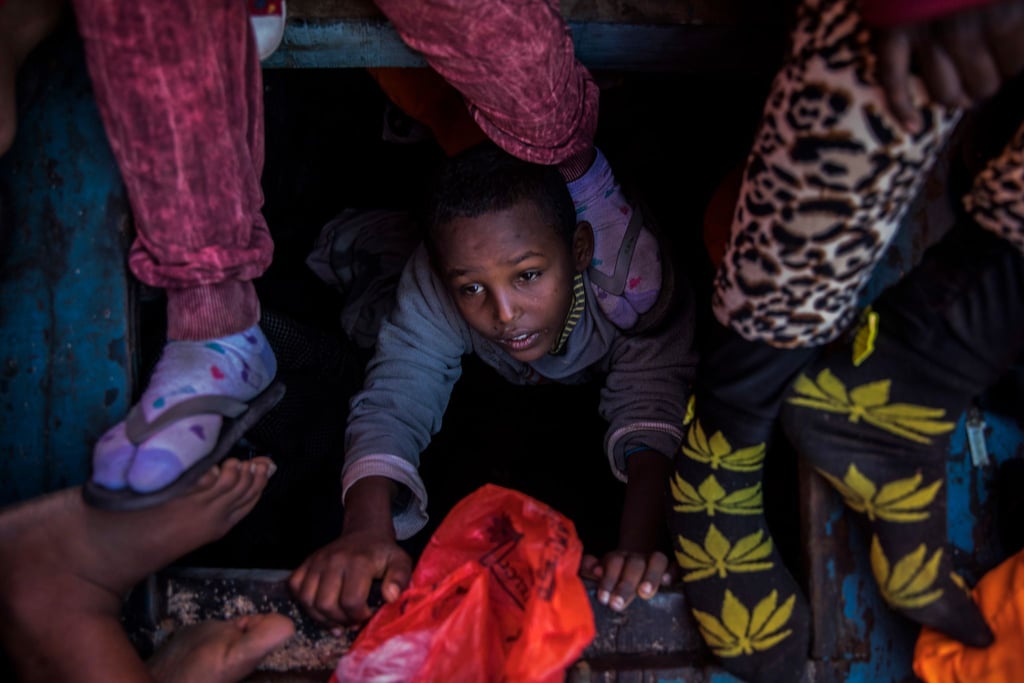 Ein Flüchtlingskind aus Eritrea versucht an der Küste zu Libyen, an Bord eines überfüllten Holzbootes hinaufzuklettern.