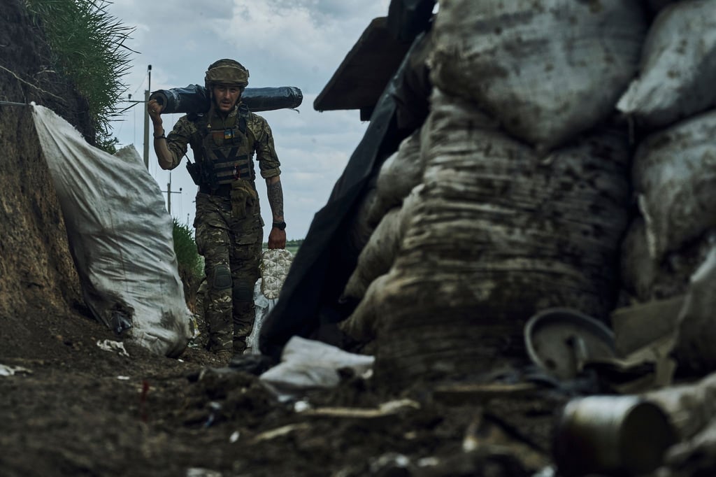 Ein ukrainischer Soldat trägt Vorräte in einem Graben an der Frontlinie bei Bachmut.