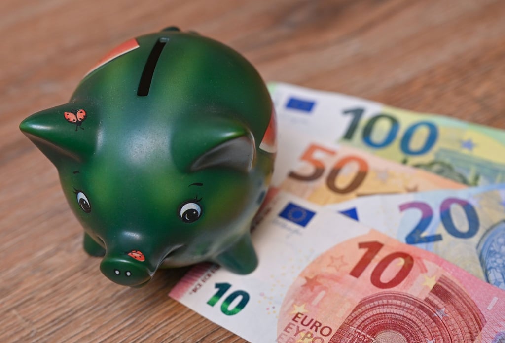 Ein Sparschwein steht auf einem Tisch neben Eurobanknoten.