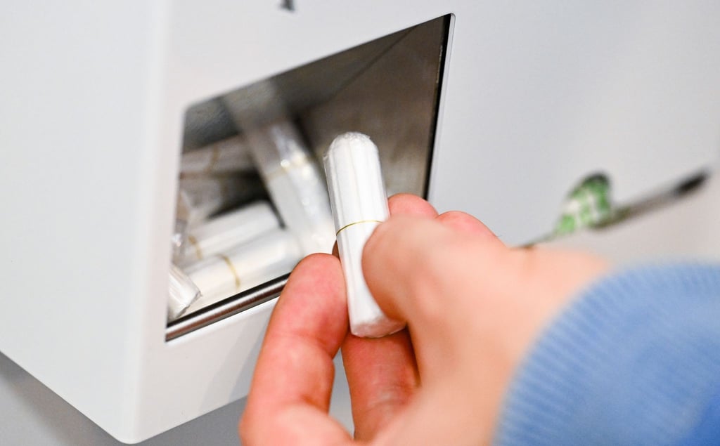 Eine Hand nimmt einen Tampon aus einem Tampon-Spender.