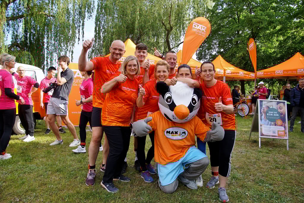 Teams von Hempelmann Haustechnik aus Schönebeck posieren beim Firmenlauf in Stendal mit dem Maskottchen Max der Dachs.