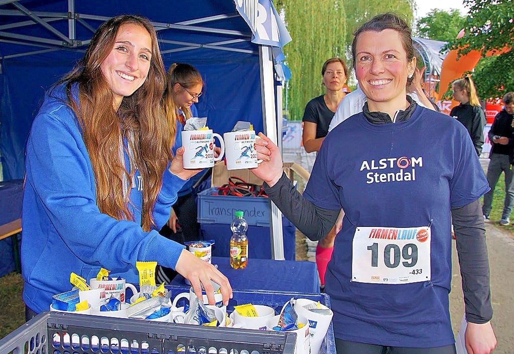 Johanna Pili (links) vom Organisationsteam verteilt an die fleißigen Läufer Tassen mit dem Aufdruck „Firmenlauf Altmark 2023“.