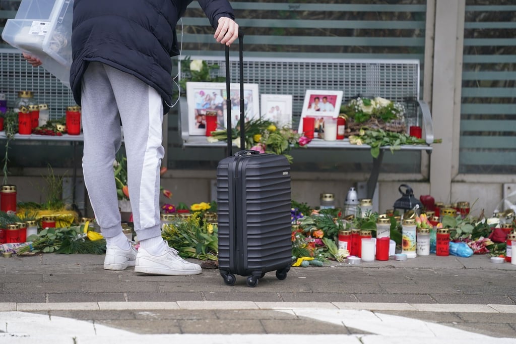 Eine Reisende schaut sich die Blumen, Kerzen und verschiedene Bilder im Wartehäuschen am Bahnhof zum Gedenken an die Opfer der Messerattacke an.