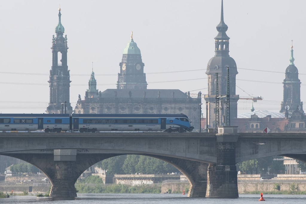 Ein sogenannter "Railjet", ein Fernverkehrszug in Kooperation mit der Tschechischen Bahn (CD) und den Österreichischen Bundesbahnen (ÖBB), fährt vor der Kulisse der Altstadt über eine Brücke.