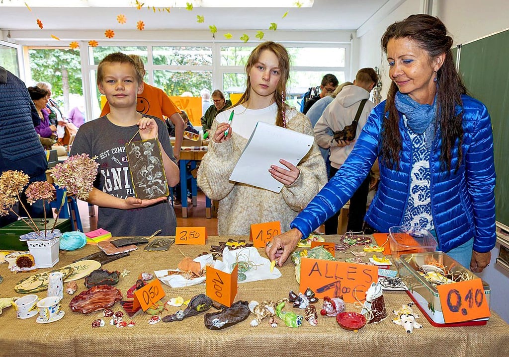 Tim und Charlijn verkaufen gemeinsam mit Monika Röhler, pädagogische Mitarbeiterin der Schule, Töpferware. De Erlös ist für die Schulfahrt.