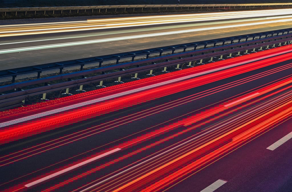 Nur die Lichtspuren von vorbei fahrenden Pkw und Lkw sind am frühen Morgen auf einer Autobahn.