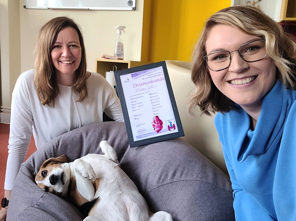 Selfie mit entspannter Hundedame. Während Beagle Elli im Körbchen liegt, überreicht Vereinsvorsitzende Stephanie Brehm an „Tierisch geborgen“-Botschafterin Vivien Job die Ehrenurkunde „Stark in Magdeburg“.