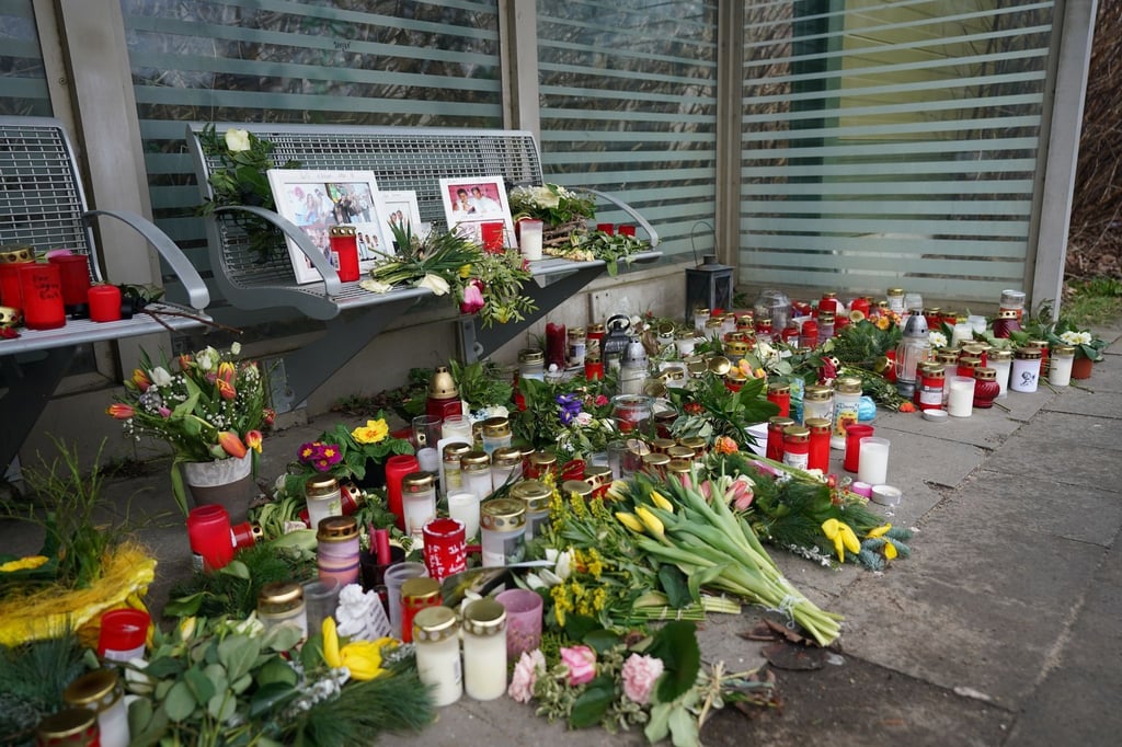 Kerzen und Blumen stehen und liegen im Bahnhof Brokstedt in einem Wartehäuschen.