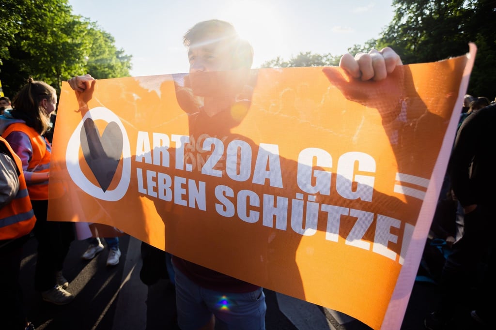 Ein Teilnehmer einer Demonstration der Letzten Generation hält bei der Kundgebung ein Banner.
