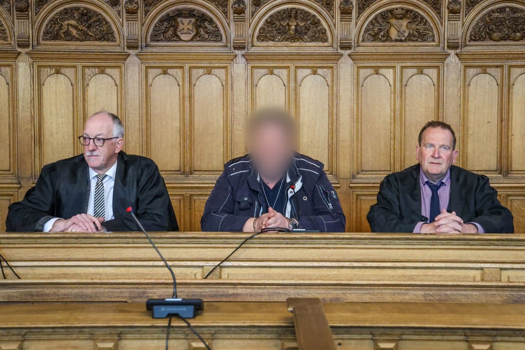 Der Angeklagte (M) sitzt vor der Urteilsverkündung im Prozess wegen Mordes im Landgericht Bremen zwischen seinen Verteidigern.