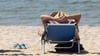 Ein Mann liegt am Strand in einem Liegestuhl.