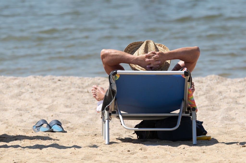 Ein Mann liegt am Strand in einem Liegestuhl.
