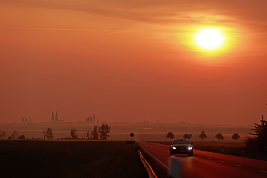 Die Sonne geht über Halberstadt auf. Im Hintergrund zeigt sich die Silhouette des Halberstädter Doms.
