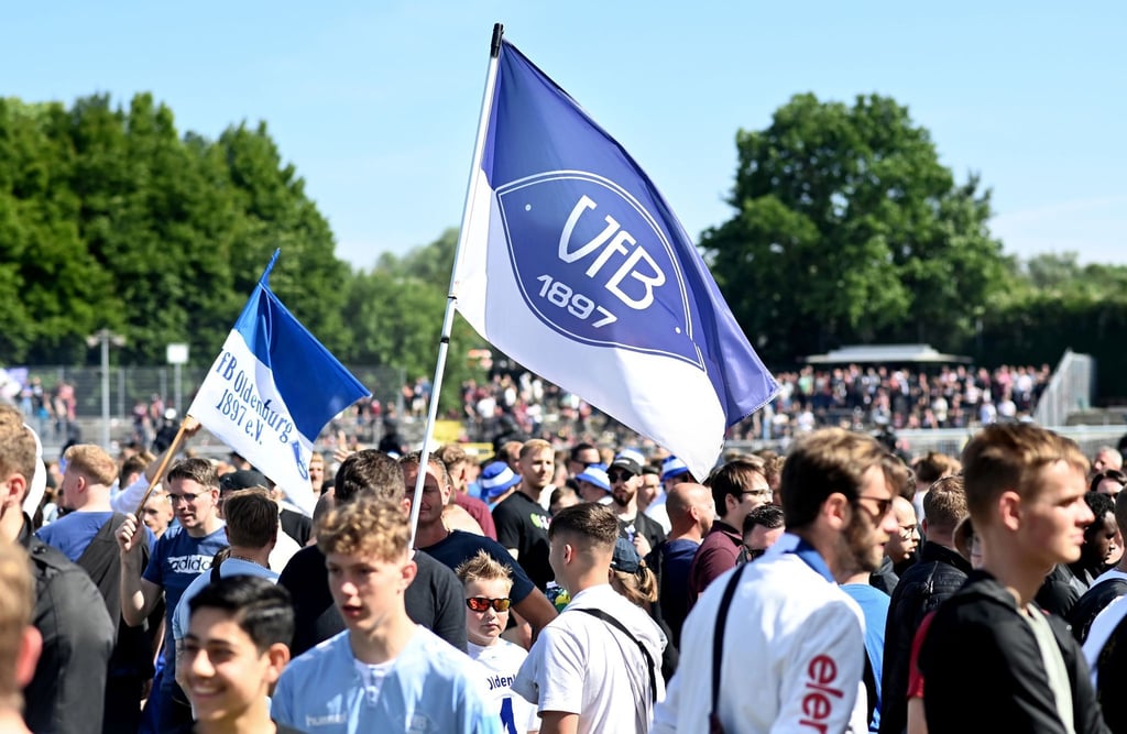 Fans vom VfB Oldenburg feiern nach dem Abpfiff auf dem Spielfeld im Stadion.