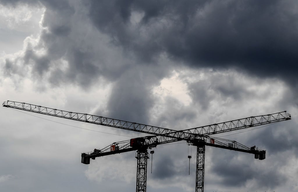 Baukräne sind vor dunklen Wolken zu sehen.