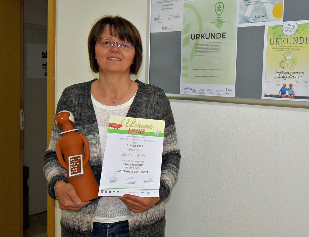 Die frischgebackene Salzlandfrau Andrea Welke zeigt stolz ihre Auszeichnung vor einer Reihe von Urkunden, die der Verein „Hecklingen - gemeinsam Zukunft gestalten" dank ihres Engagements erhalten hat.