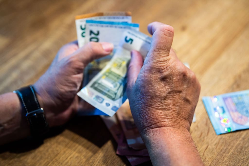 Ein Mann zählt Geld an einem Tisch.