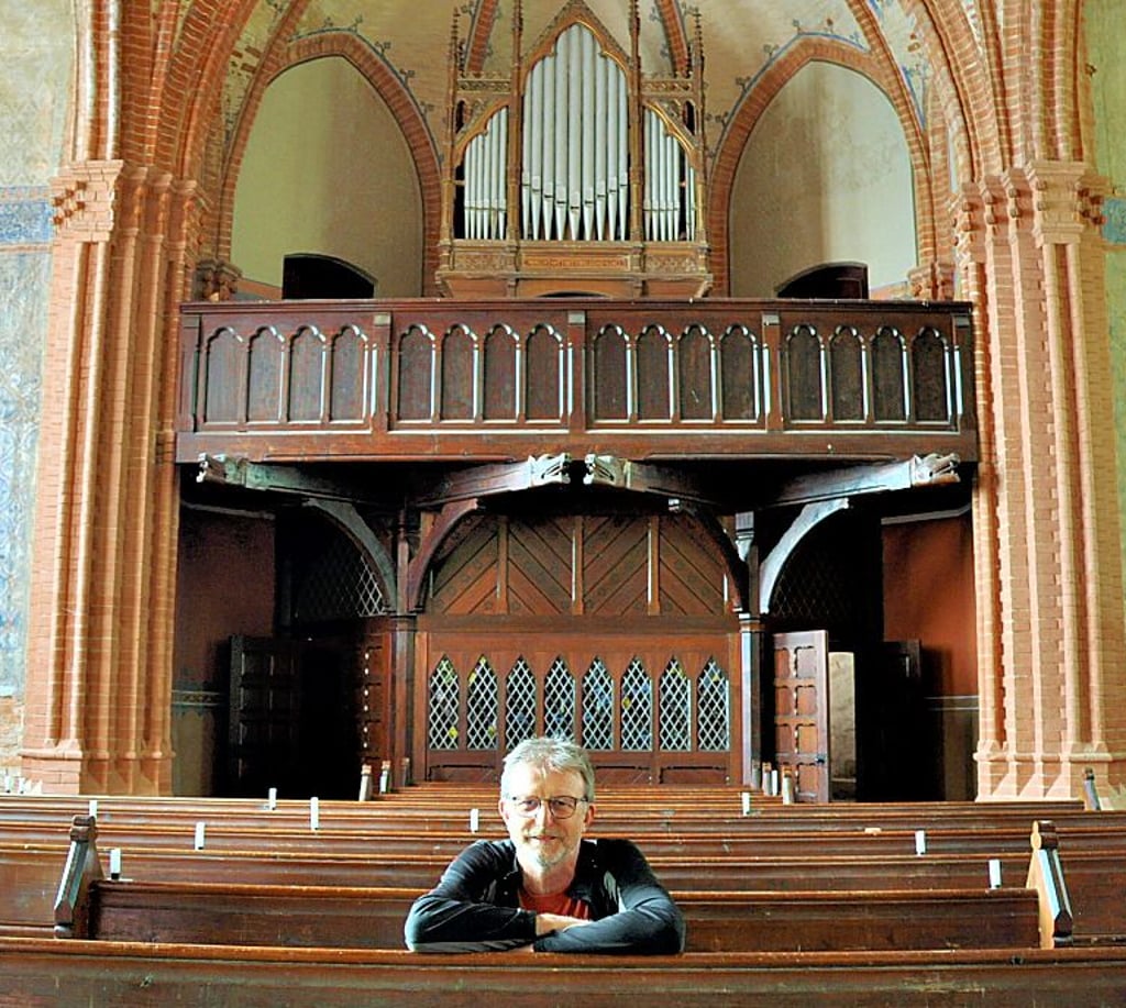 Vereinsvorsitzender Thomas Rehbein sitzt in der Vollenschierer Kirche. Im Hintergrund ist die Original-Orgel zu sehen.