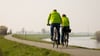 Ein Fahrradfahrer und eine Fahrradfahrerin sind auf dem Weser-Radweg unterwegs.