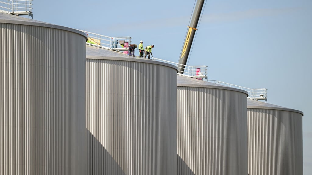 Arbeiter stehen auf einem Behälter, bei dem Bau einer riesigen Biogasanlage.