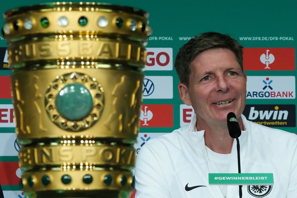 Oliver Glasner, Cheftrainer von Eintracht Frankfurt, lächelt während der Pressekonferenz hinter dem Pokal.