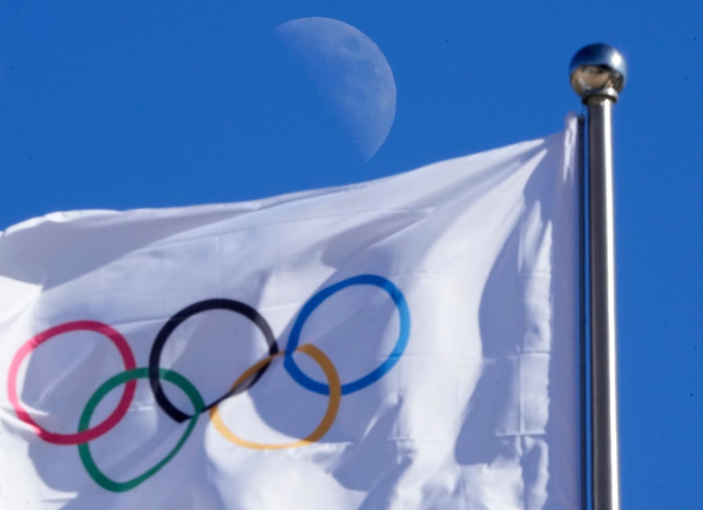 Eine olympischen Flagge weht vor blauem Himmel im Wind.