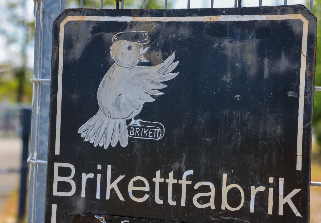 Ein Schild ist vor der ehemaligen Brikettfabrik Herrmannschaft zu sehen.