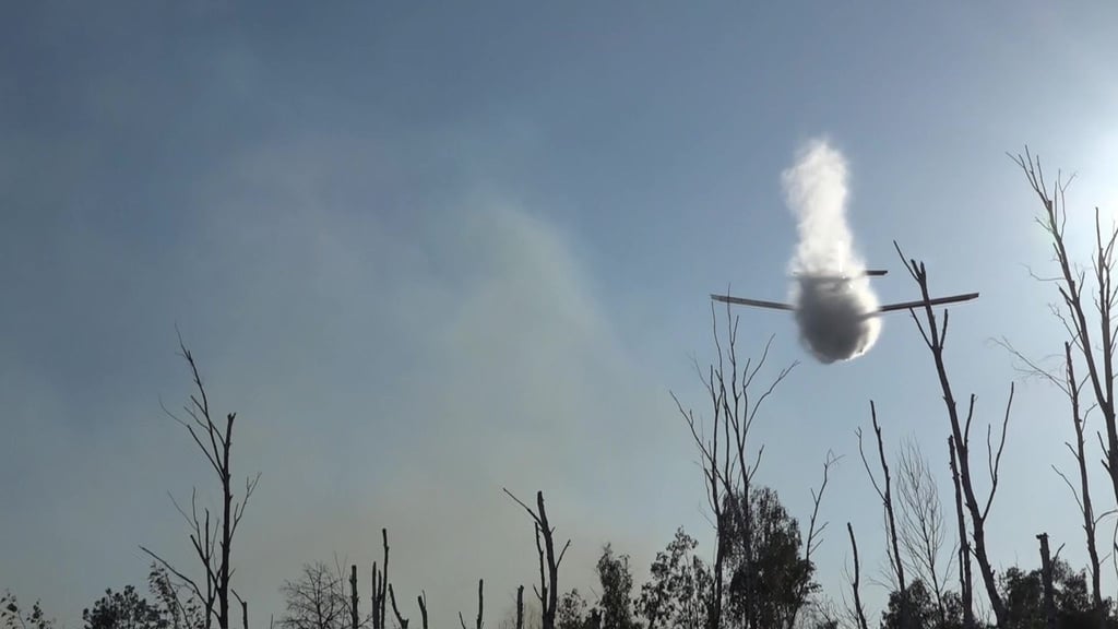 Ein kleines Löschflugzeug wirft Wasser ab über einem Waldbrand in einem munitionsbelasteten Gebiet bei Jüterbog (Landkreis Teltow-Fläming).