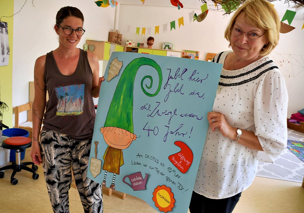 Kita-Leiterin Kerstin Hamann (rechts) und Erzieherin Alexandra Maas zeigen das Plakat, mit dem die Havelberger Kita zum 40. Geburtstag willkommen heißt.