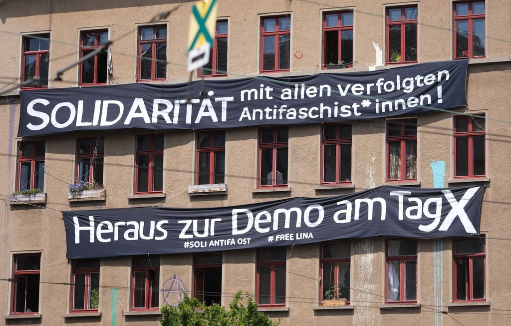 Transparente mit der Aufschrift „Solidarität mit allen verfolgten Antifaschist*innen!“ und „Heraus zur Demo am Tag X“ hängen an der Fassade eines Hauses im Osten der Stadt.