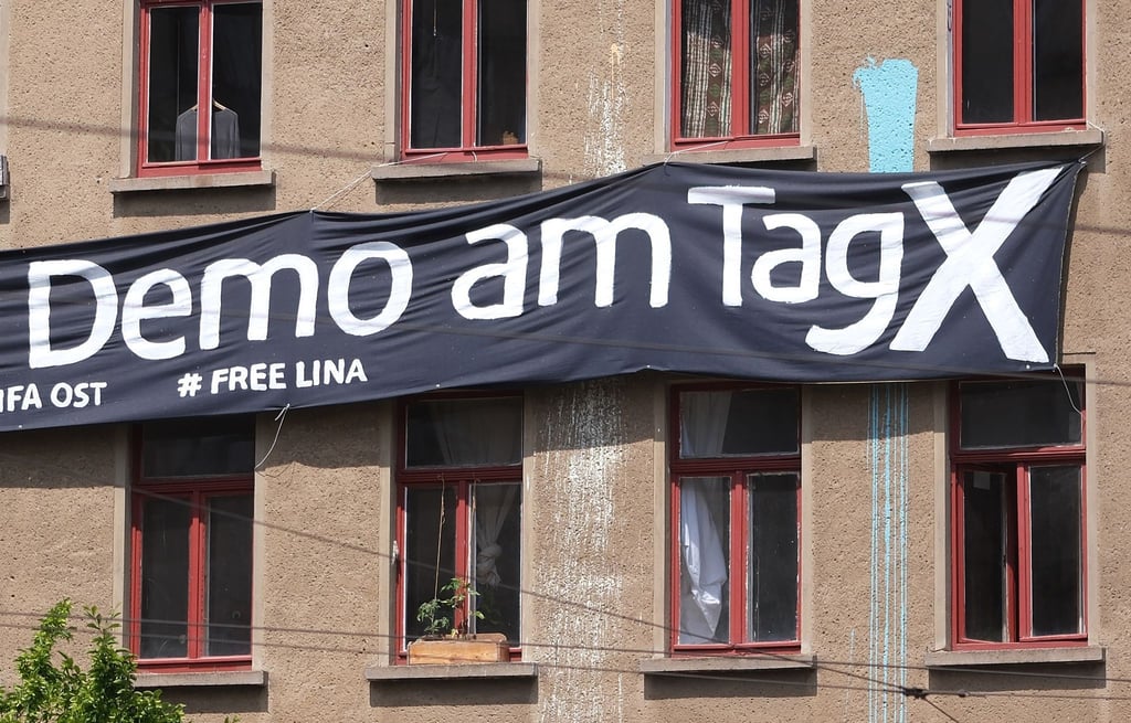 Ein Transparent mit der Aufschrift "Demo am Tag X“ und "# Free Lina" hängt an der Fassade eines Hauses im Osten der Stadt.