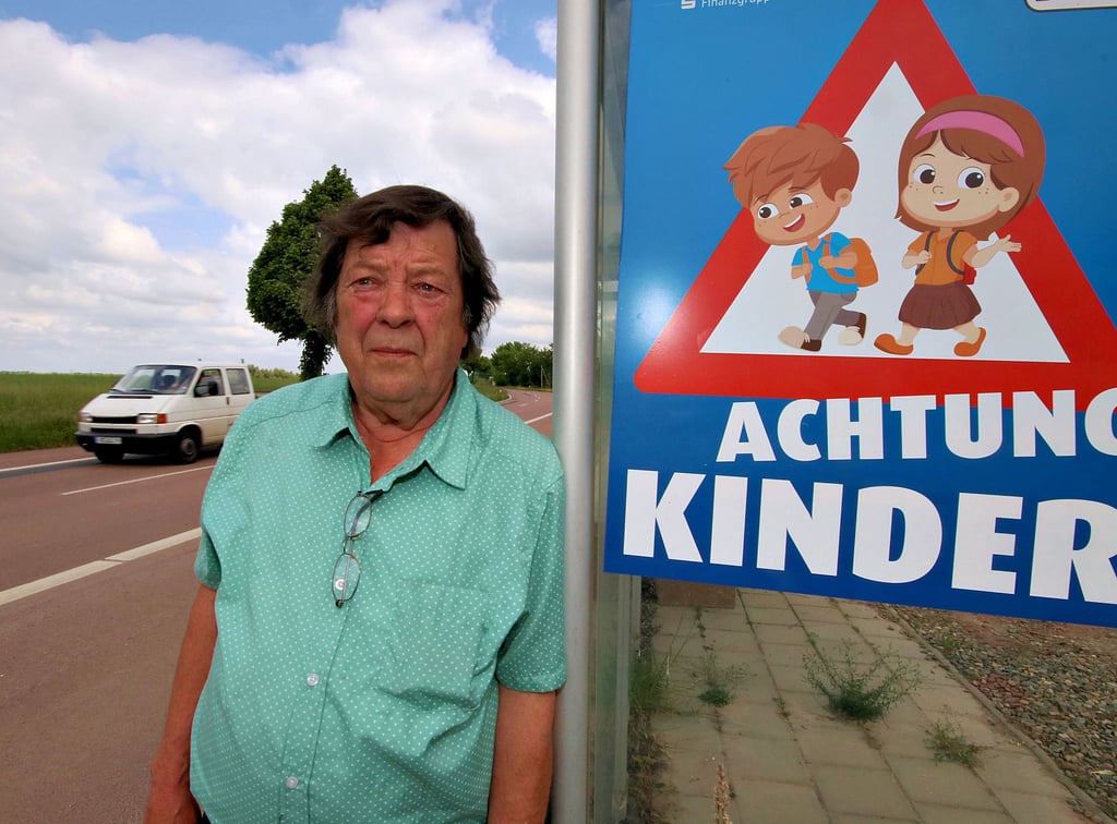Lothar Schröder steht an einer der beiden Bushaltestelen in der Siedlung. Große Plakate hat er hier angebracht, um die Autofahrer auf Kinder aufmerksam zu machen.