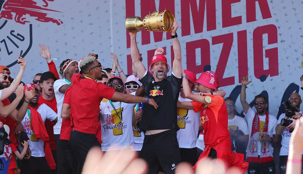 RB-Coach Marco Rose zeigt den Pott im Kult-Outfit den Fans.