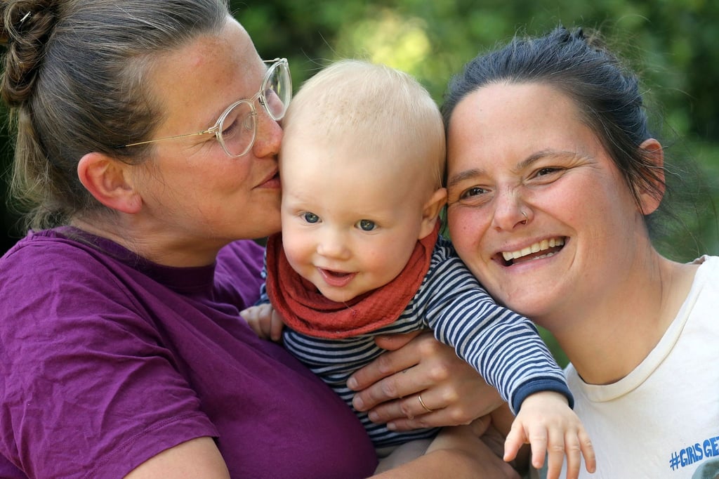 Juliane (l-r), der zehn Monate alte Remo und Jana in ihrem Garten hinter ihrem Haus in Berlin.