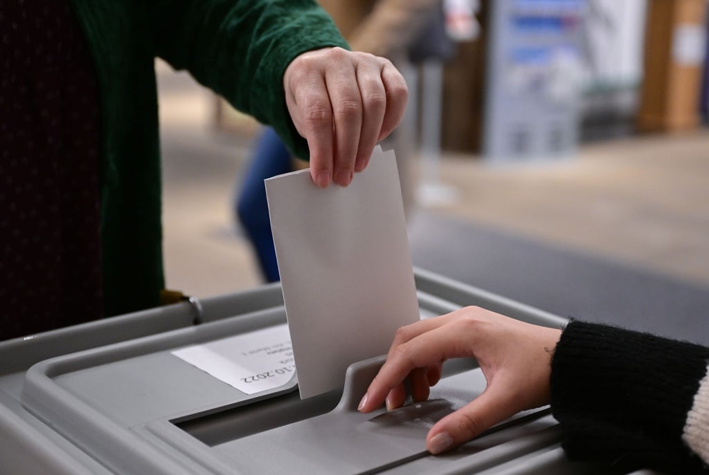 Ein Wähler steckt bei einer Wahl seinen Wahlzettel in eine Urne.