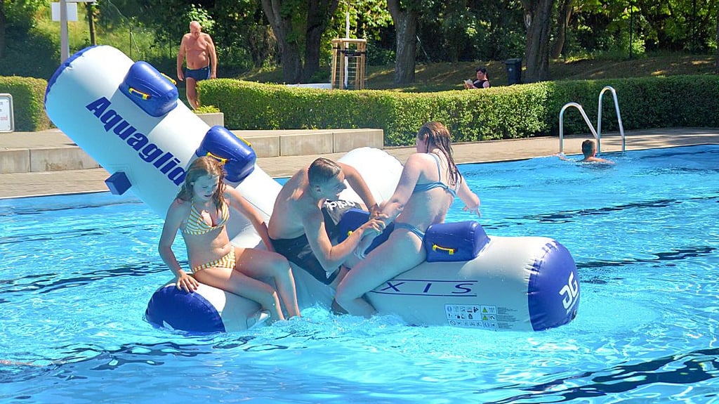 Die etwas älteren Jugendlichen toben sich im Freibad mit den Wasserspielgeräten aus.