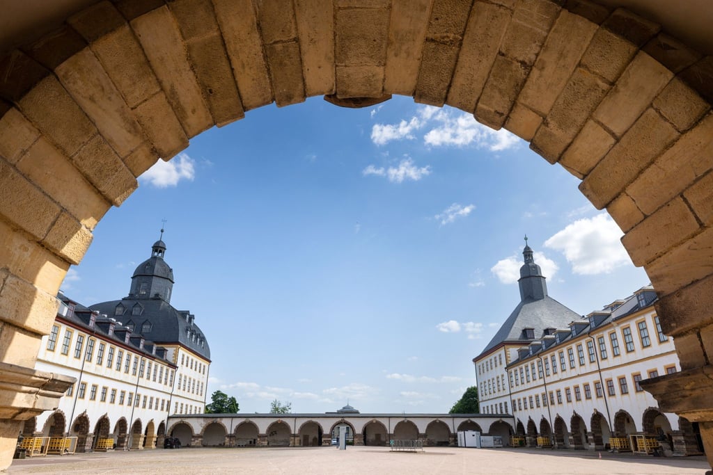 Durch einen Torbogen sind die Türme von Schloss Friedenstein zu sehen.