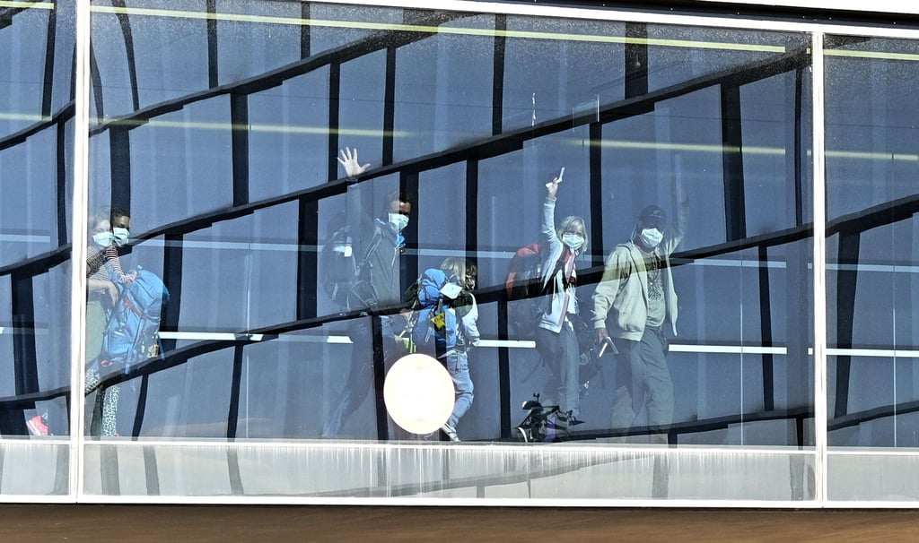 Passagiere mit Mundschutz winken auf dem Flughafen Wien-Schwechat im Jahr 2020.