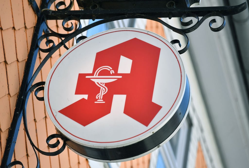 Das Apothekenzeichen hängt an einer Hausfassade.