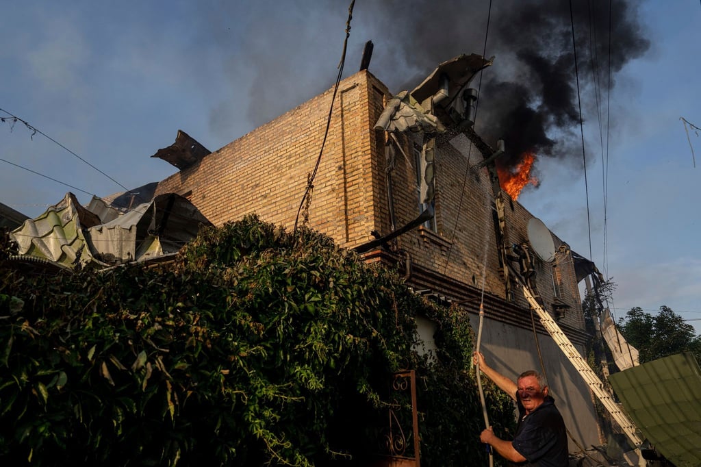 Ein Anwohner löscht ein Feuer in einem Haus, das nach russischem Beschuss in Cherson, Ukraine, beschädigt wurde.