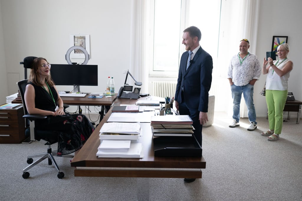 Michael Kretschmer (CDU, M), Ministerpräsident von Sachsen, steht vor Emily Schön (l), Besucherin.