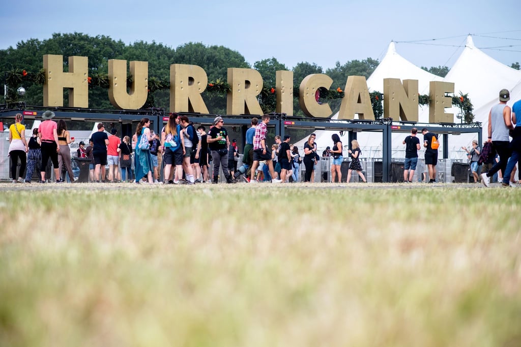 Zahlreiche Festivalbesucher gehen 2022 am Haupteingang des Hurricane Festivals an einem großen Schriftzug.