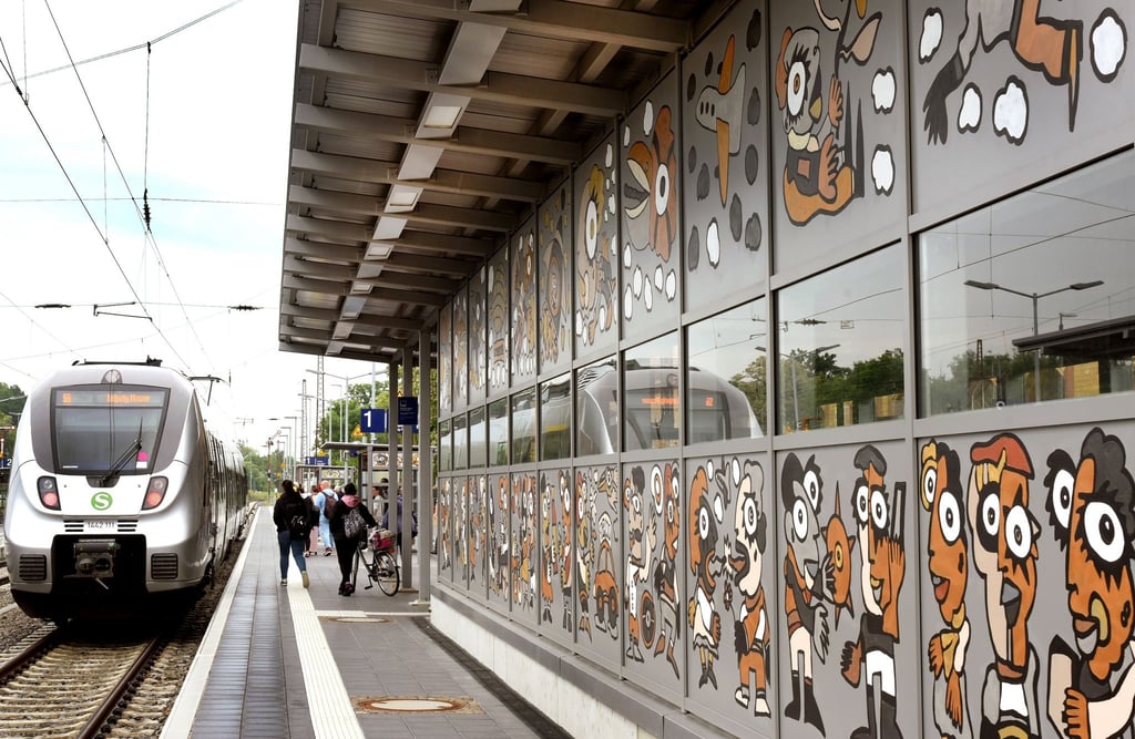 Im Bahnhof Borna fährt eine S-Bahn an einer vom Künstler Michael Fischer-Art bemalten Wand am Bahnsteig 1 vorbei.