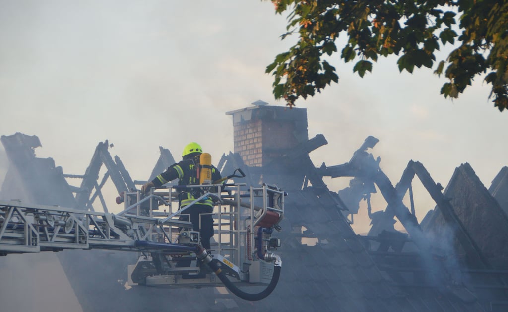 Vom Korb der Drehleiter aus nehmen Kameraden den Dachstuhlbrand ins Visier.